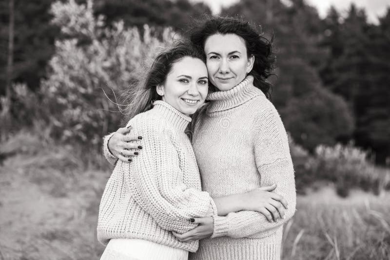 Foto en blanco y negro con chicas abrazándose. dos brunettes en sudaderas calientes. relaciones estrechas entre las hermanas foto de archivo