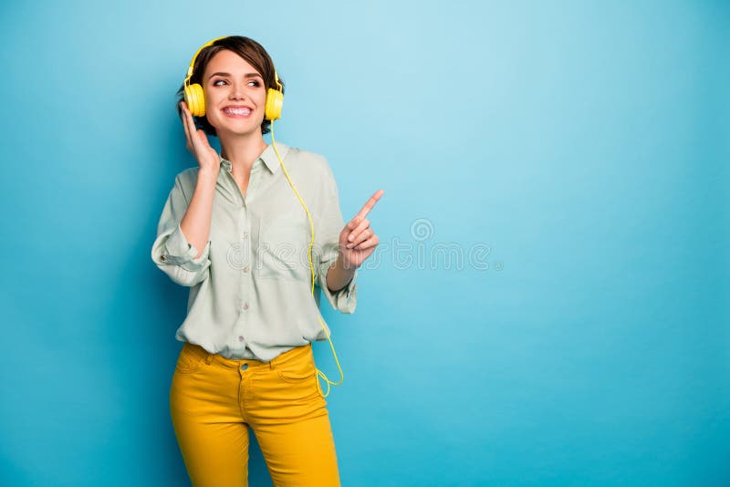 Foto netter Dame hören elegante Radiokopfhörer erhöhen den Finger, der das zufällige Green Gelbe Trikot der leeren Raumabnutzung