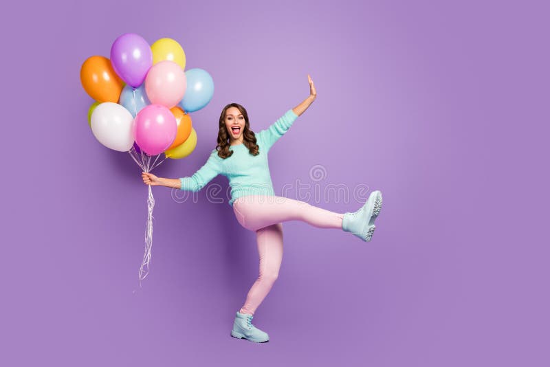 Full size photo of funny feminine girl enjoy occasion celebrate her friends, anniversary hold many air baloons scream wear pastel soft trend boots isolated over violet color background. Full size photo of funny feminine girl enjoy occasion celebrate her friends, anniversary hold many air baloons scream wear pastel soft trend boots isolated over violet color background