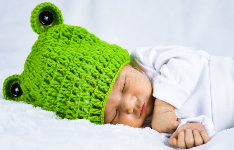 Foto principal ascendente próxima de um bebê recém-nascido adorável de vista feliz bonito com tampão verde imagem de stock royalty free Foto principal ascendente próxima de um bebê recém-nascido adorável de vista feliz bonito com tampão verde imagem de stock royalty free