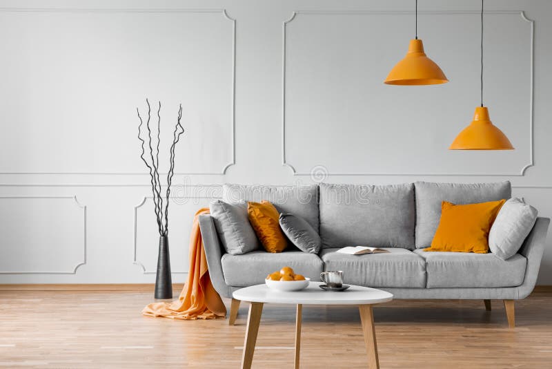 Foto reale del salone semplice interna con le lampade arancio, i cuscini ed il sofà grigio immagine stock