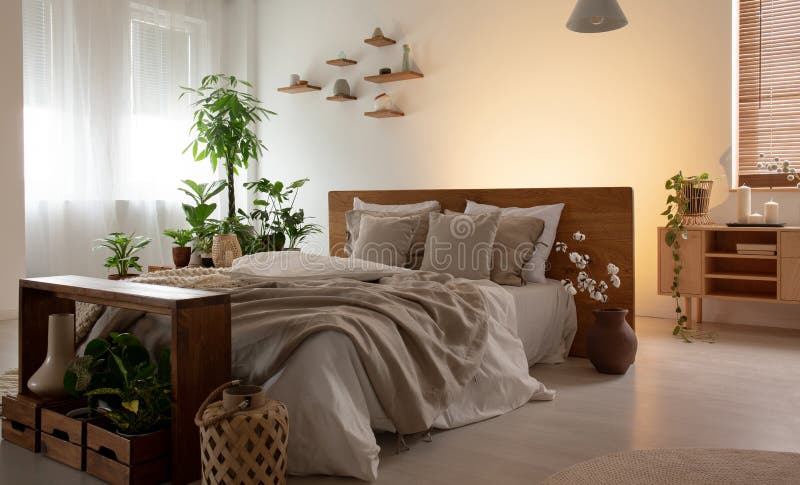 Foto reale di un interno romantico della camera da letto con un letto matrimoniale con gli strati, le piante e gli scaffali di le immagini stock libere da diritti Foto reale di un interno romantico della camera da letto con un letto matrimoniale con gli strati, le piante e gli scaffali di le immagini stock libere da diritti
