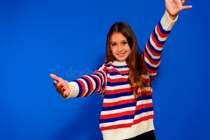 Foto ritratto di una bambina che tiene la mano in avanti abbracciando uno sfondo di colore blu isolato. fotografia stock libera da diritti