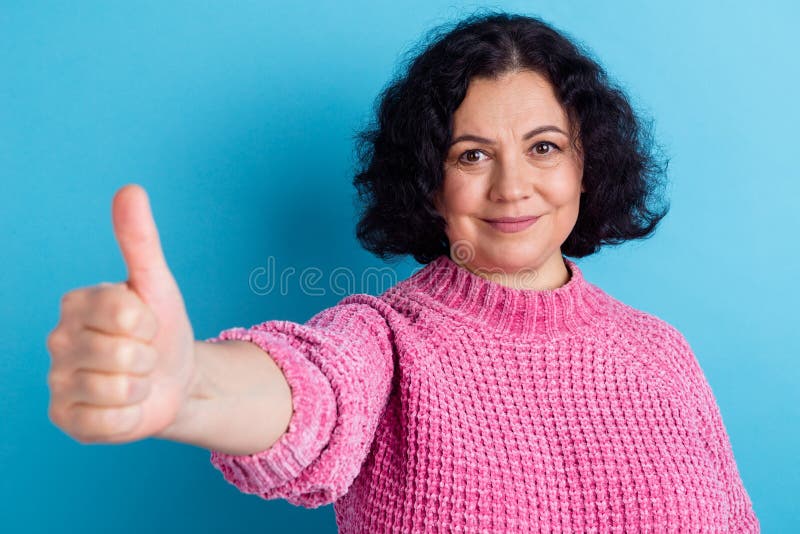 Foto ritratto di una donna anziana che mostra il gesto del thumbup sorridendo di uno sfondo di colore blu pastel fotografia stock