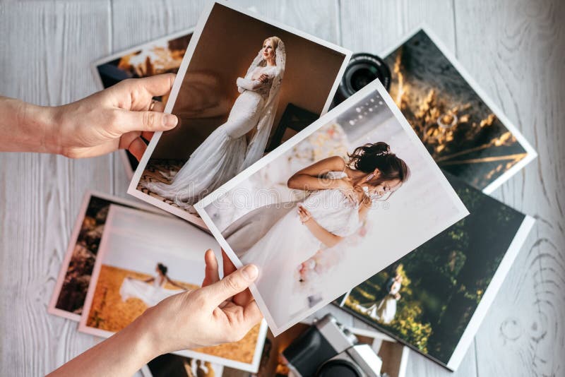 Foto stampate di nozze con la sposa e lo sposo, una macchina fotografica nera d'annata e mani della donna con due foto immagini stock Foto stampate di nozze con la sposa e lo sposo, una macchina fotografica nera d'annata e mani della donna con due foto immagini stock