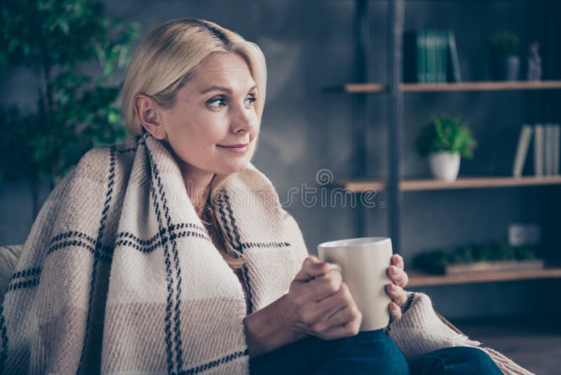 Foto sul profilo di una donna di mezza età, calma e tranquilla, seduta in salotto di una tazza di tazza con un caffè caldo fotografia stock Foto sul profilo di una donna di mezza età, calma e tranquilla, seduta in salotto di una tazza di tazza con un caffè caldo fotografia stock
