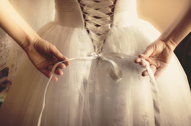 Foto tonificata di bella sposa che lega il suo vestito da sposa