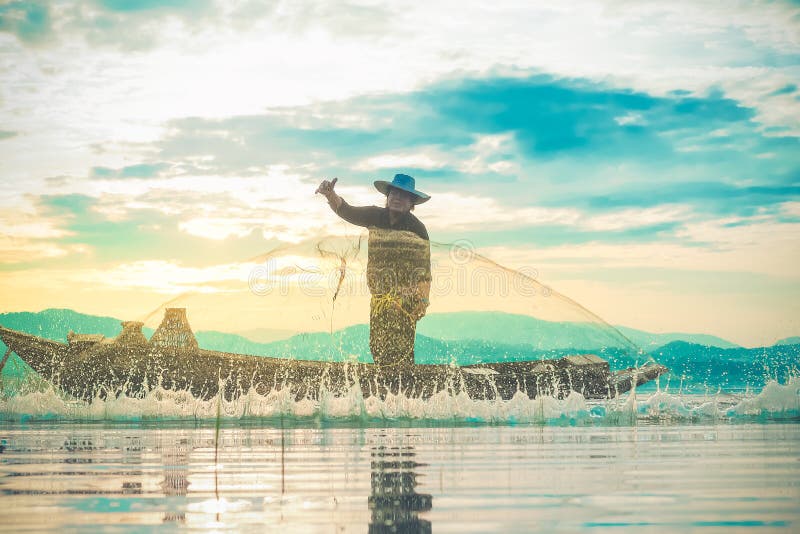 Foto van de waterspatter van de visser tijdens het gooien van het visnet op het meer Silhouette van vissers met visnet in stock fotografie Foto van de waterspatter van de visser tijdens het gooien van het visnet op het meer Silhouette van vissers met visnet in stock fotografie