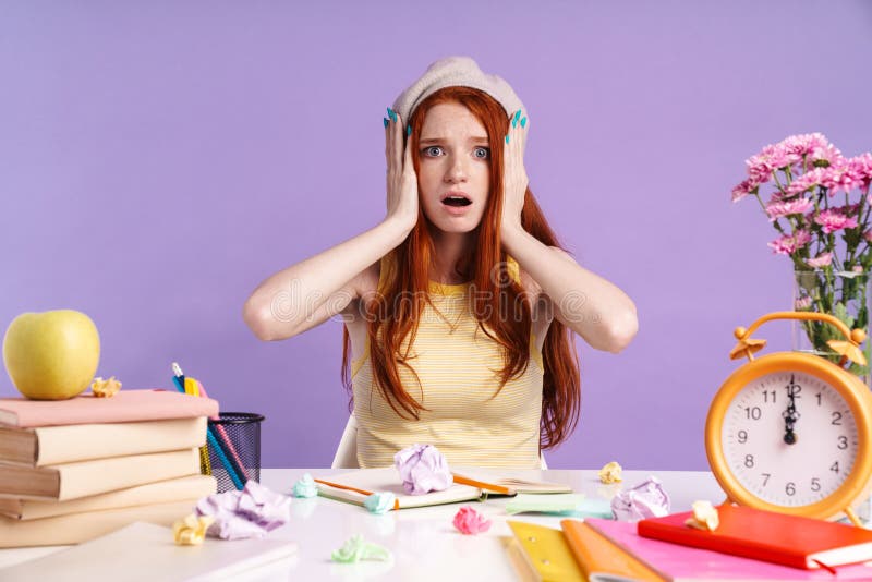 Foto van een teleurgesteld studentenmeisje dat haar hoofd met boeken aan het bureau vasthoudt stock afbeeldingen Foto van een teleurgesteld studentenmeisje dat haar hoofd met boeken aan het bureau vasthoudt stock afbeeldingen