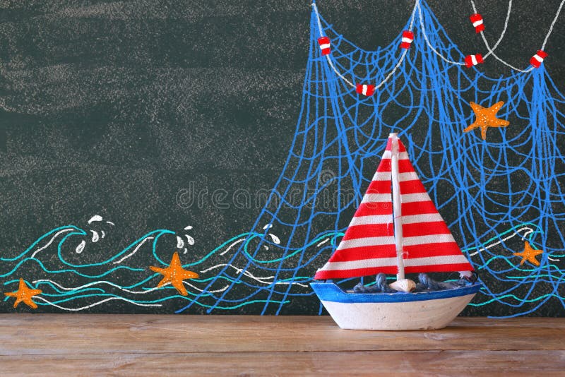 Foto van houten varende boot voor bord met zeevaartillustraties stock afbeelding Foto van houten varende boot voor bord met zeevaartillustraties stock afbeelding