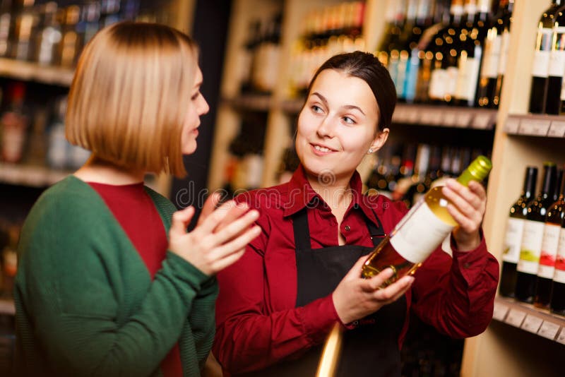 Foto van twee jonge vrouwen met fles in handen bij slijterij stock foto Foto van twee jonge vrouwen met fles in handen bij slijterij stock foto