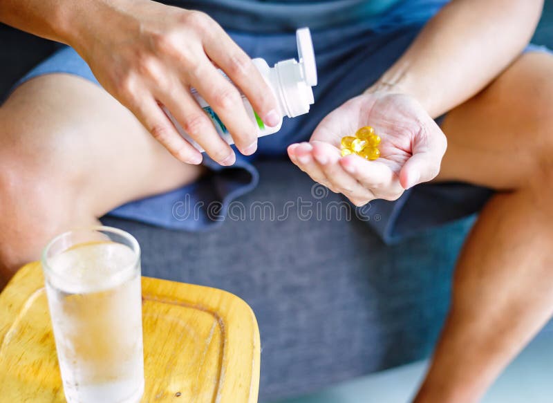 Foto van één ronde gele pil ter beschikking De mens neemt geneesmiddelen met glas water Dagelijkse norm van vitaminen, efficiënte