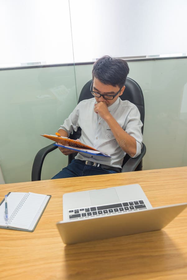 Foto vertical de dados financeiros de leitura do homem de negócios asiático no relatório fotografia de stock royalty free Foto vertical de dados financeiros de leitura do homem de negócios asiático no relatório fotografia de stock royalty free