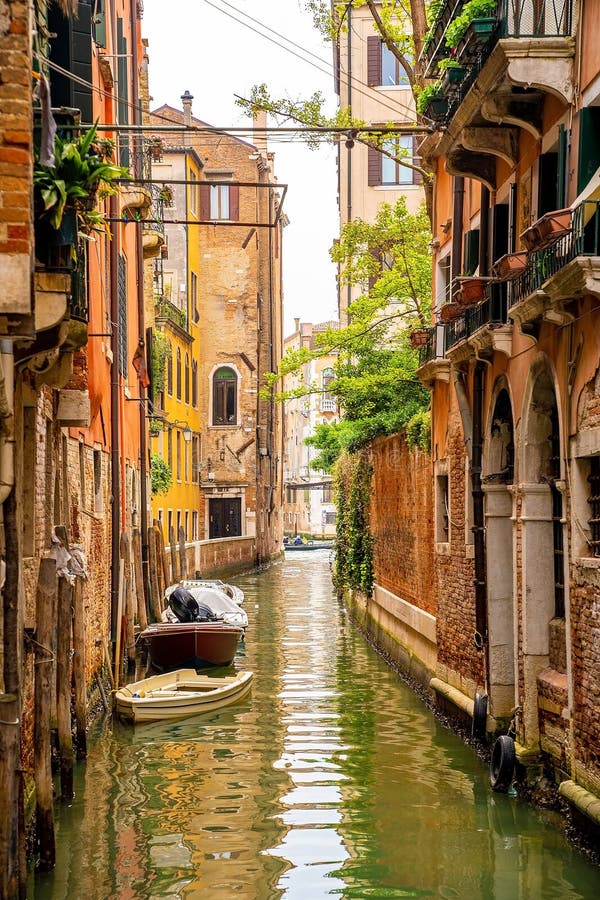 Foto verticale di un canale in venezia italia con barche e vecchie case