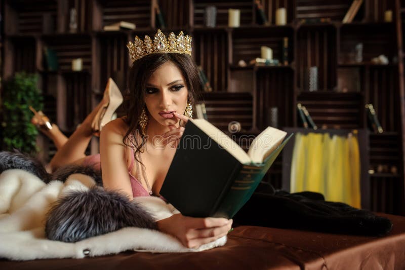 Foto von einer sexy Frau, die auf einem weißen Pelzmantel mit grauem Halsband in rosa Unterhosen mit einer Krone auf ihrem Kopf Nä Foto von einer sexy Frau, die auf einem weißen Pelzmantel mit grauem Halsband in rosa Unterhosen mit einer Krone auf ihrem Kopf Nä