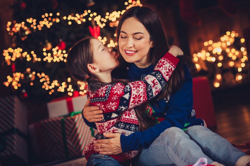 Foto von süße Mutter kleine Tochter küssen Wange kuscheln gekleidet Weihnachtskleidung Tradition Atmosphäre Dekoration Haus stockbild