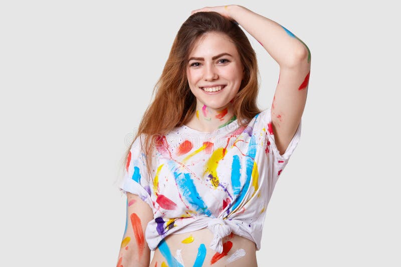 Fotoet av den gladlynta kvinnliga konstnären känner sig glat, och tillfredsställt, når att ha målat bilden, bär den tillfälliga ö arkivbild