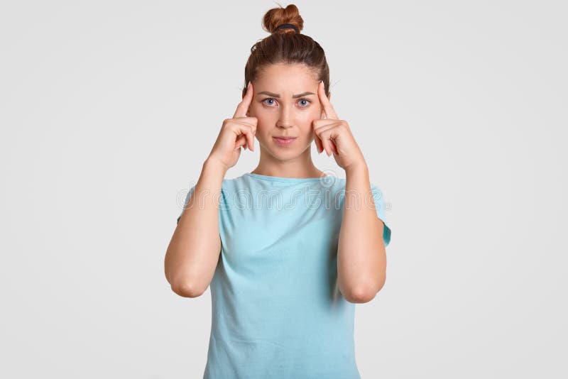 Fotoet av den koncentrerade unga kvinnliga modellen försöker till focuse på nödvändig information, håller båda pekfingrar på temp arkivbilder Fotoet av den koncentrerade unga kvinnliga modellen försöker till focuse på nödvändig information, håller båda pekfingrar på temp arkivbilder