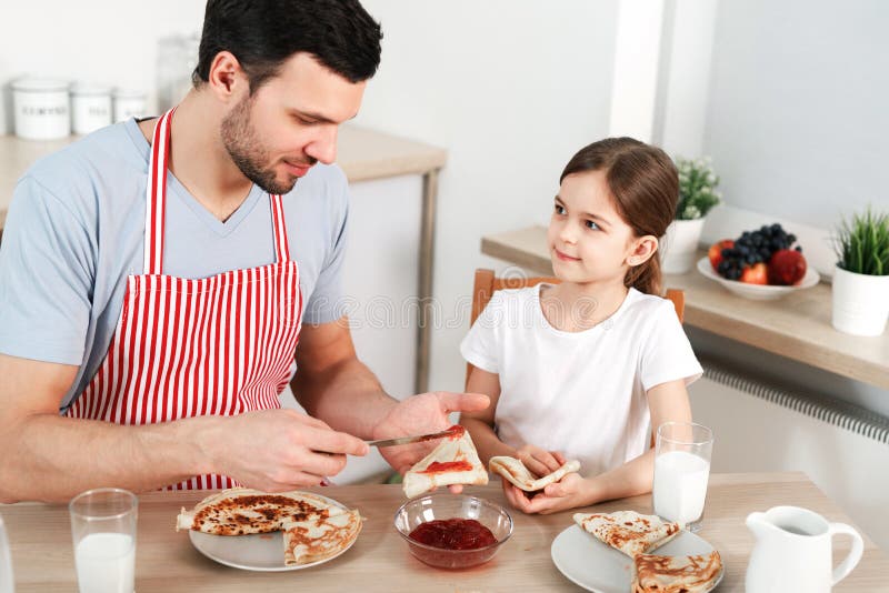 Fotoet av den vänliga familjen har frukosten tillsammans Skäggiga manspridningar sitter fast på den tunna stekte pannkakan, sitte arkivfoton Fotoet av den vänliga familjen har frukosten tillsammans Skäggiga manspridningar sitter fast på den tunna stekte pannkakan, sitte arkivfoton