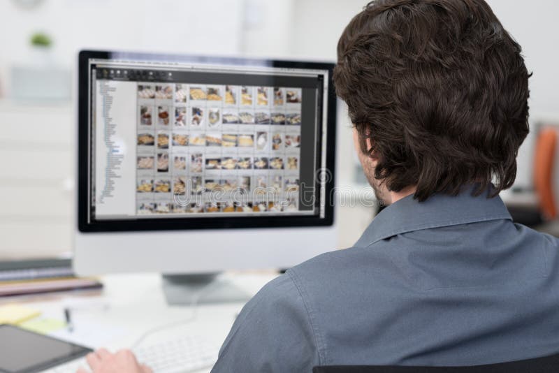 Fotograf, der Fotos auf einem Computer redigiert stockbild Fotograf, der Fotos auf einem Computer redigiert stockbild