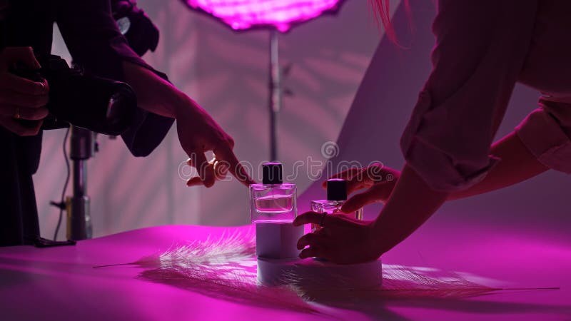 Fotograf i projektant strzelający perfumy pod purpurowym oświetleniem zdjęcie royalty free