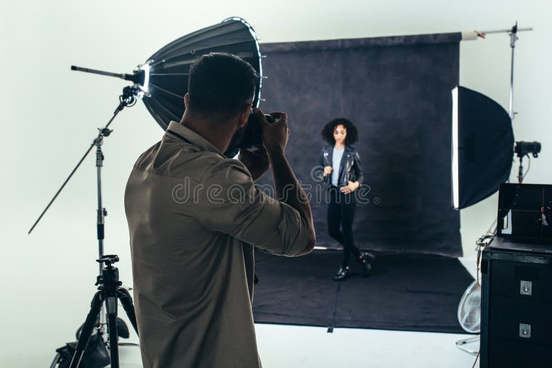 Model posing for a photograph during a photo shoot. Studio shot of a photographer shooting photos of a women with studio flash lights on. Model posing for a photograph during a photo shoot. Studio shot of a photographer shooting photos of a women with studio flash lights on.