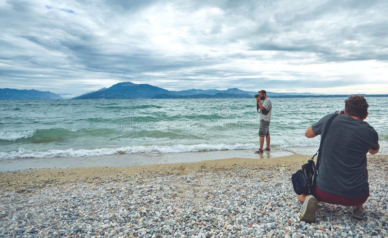 Fotografen die op het overzeese strand bij bewolkte dag schieten royalty-vrije stock afbeelding Fotografen die op het overzeese strand bij bewolkte dag schieten royalty-vrije stock afbeelding