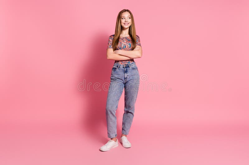 Full length photo of positive girl wear print t-shirt holding arms folded look at sale empty space isolated on pink color background. Full length photo of positive girl wear print t-shirt holding arms folded look at sale empty space isolated on pink color background.