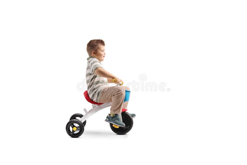 Fotografie de profil completă a unui băiat care călărește o tricicletă stock photos