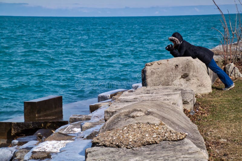 Fotografo della donna che cattura le onde che spruzzano dal lago Michigan immagine stock Fotografo della donna che cattura le onde che spruzzano dal lago Michigan immagine stock