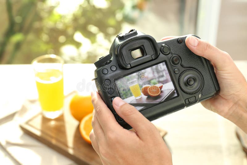 Fotografo femminile che prende immagine di succo e delle arance con la macchina fotografica professionale fotografie stock Fotografo femminile che prende immagine di succo e delle arance con la macchina fotografica professionale fotografie stock