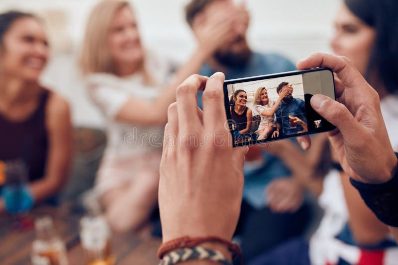 Fotografować przyjaciół przy przyjęciem z telefonem komórkowym obraz stock Fotografować przyjaciół przy przyjęciem z telefonem komórkowym obraz stock