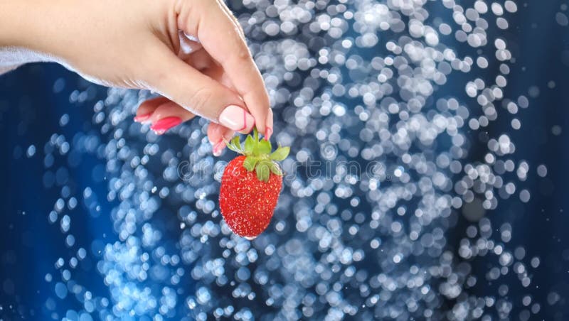 Fotografía de una mano de mujer encerrar con fresa roja bajo gotas de agua. niña mostrando fresa roja almacen de video