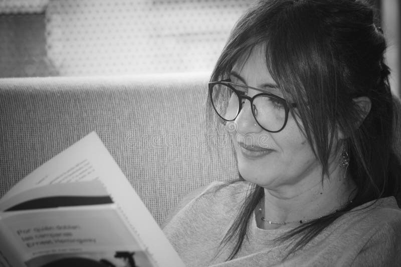 Fotografía de una mujer blanca leyendo un libro relajado en su sillón en casa. imagen de archivo libre de regalías Fotografía de una mujer blanca leyendo un libro relajado en su sillón en casa. imagen de archivo libre de regalías
