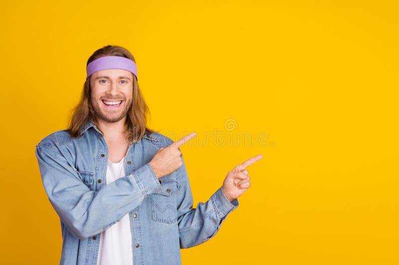 Photo portrait of attractive young hippie man point empty space wear trendy denim outfit isolated on yellow color background. Photo portrait of attractive young hippie man point empty space wear trendy denim outfit isolated on yellow color background.
