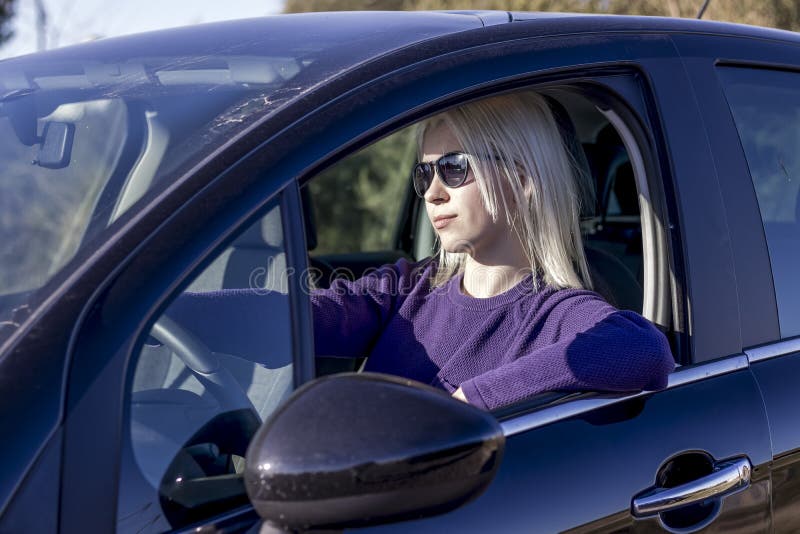 Fotoporträtt med solglasögon som håller ratten i bilen royaltyfria foton