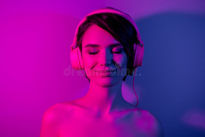 Fotoporträttet Lugn, söt flicka under skulor med bob hårstil lyssna musik isolerad neon-rosa färgbakgrund royaltyfria foton