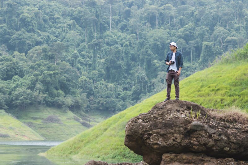Fotvandra den unga asiatiska handelsresanden man att ta fotoet på den sceniska bergbakgrunden för vagga utomhus Livsstil och avko royaltyfria foton Fotvandra den unga asiatiska handelsresanden man att ta fotoet på den sceniska bergbakgrunden för vagga utomhus Livsstil och avko royaltyfria foton