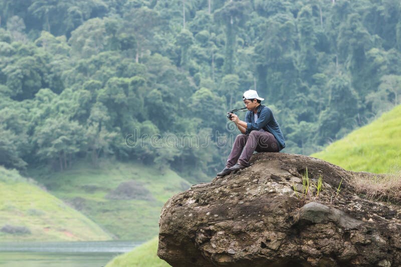 Fotvandra den unga asiatiska handelsresanden man att ta fotoet på den sceniska bergbakgrunden för vagga utomhus Livsstil och avko fotografering för bildbyråer Fotvandra den unga asiatiska handelsresanden man att ta fotoet på den sceniska bergbakgrunden för vagga utomhus Livsstil och avko fotografering för bildbyråer