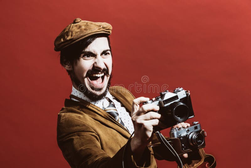 Fotógrafo muito positivo que levanta no estúdio com câmeras fotografia de stock royalty free Fotógrafo muito positivo que levanta no estúdio com câmeras fotografia de stock royalty free