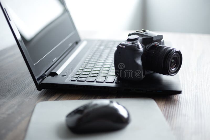 Fotógrafo ou conceito conservado em estoque da fotografia, câmera preta digital perto do portátil na estação de trabalho da mesa foto de stock Fotógrafo ou conceito conservado em estoque da fotografia, câmera preta digital perto do portátil na estação de trabalho da mesa foto de stock