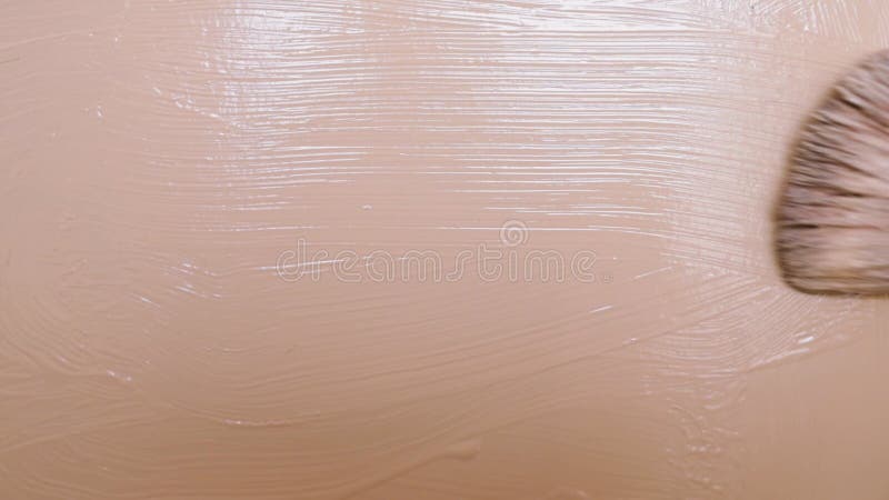 Beige smear of tonal foundation cream close up, smudge with a brush, beautiful pastel texture, cosmetic product for make up