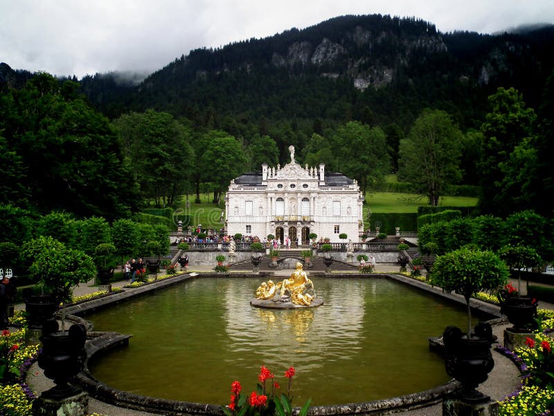 Linderhof, Germany - July 7, 2015: The fountain in front of the Linderhof Castle. Gloomy weather in the forest. Castle in the Alps