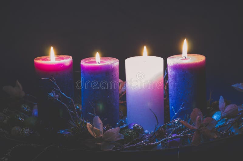 Four advent candles burning on black background stock images.