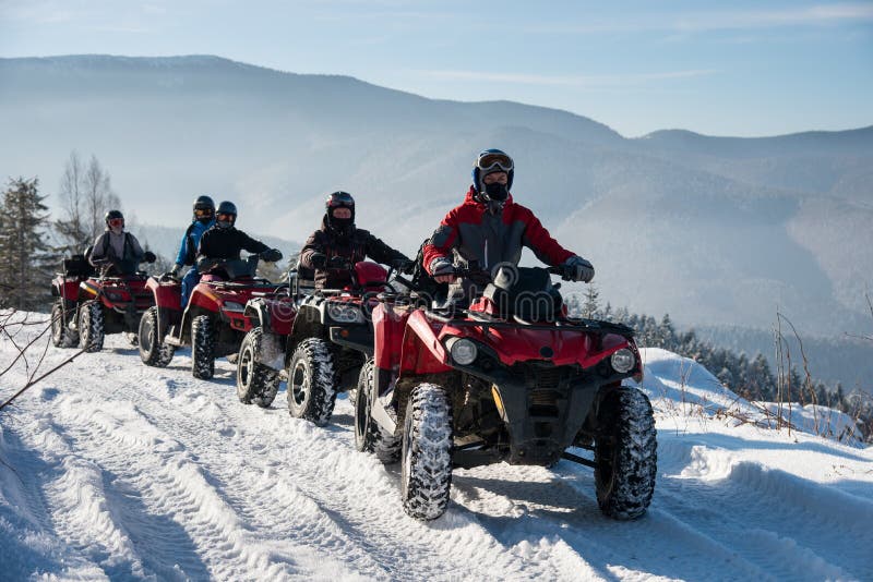 Four ATV riders on off-road four-wheelers ATV bikes in the winter mountains