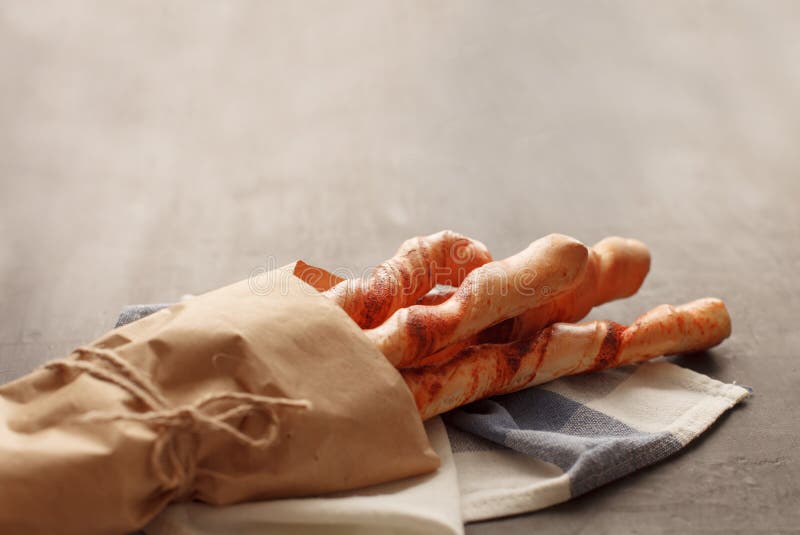 Four baguettes in wrapping paper tied with twine lie on the table