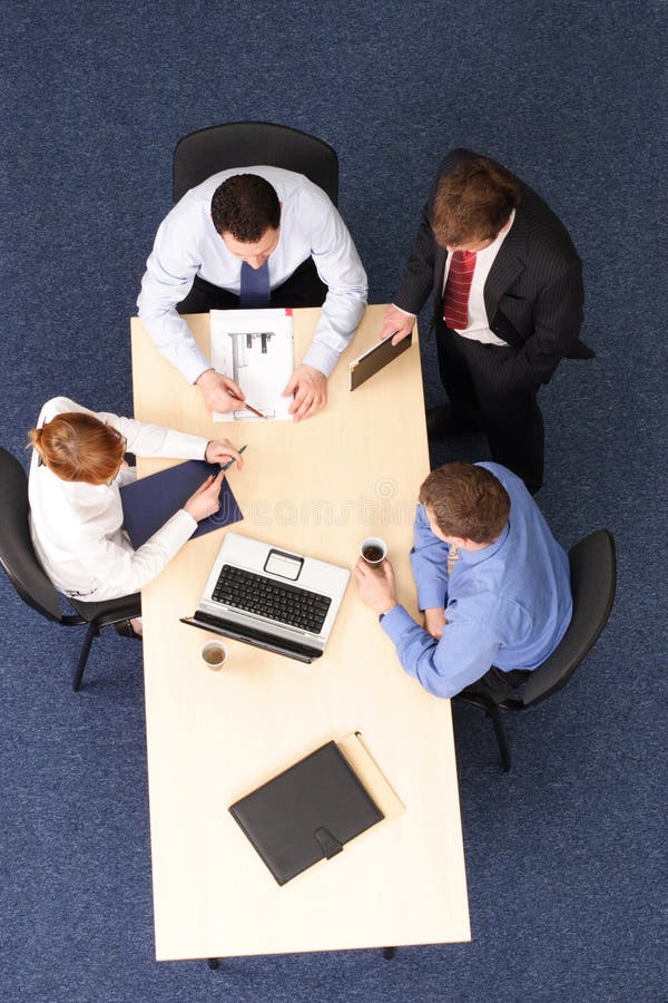 Businesspeople gathered around a table for a meeting, brainstorming. Aerial shot taken from directly above the table. Businesspeople gathered around a table for a meeting, brainstorming. Aerial shot taken from directly above the table.