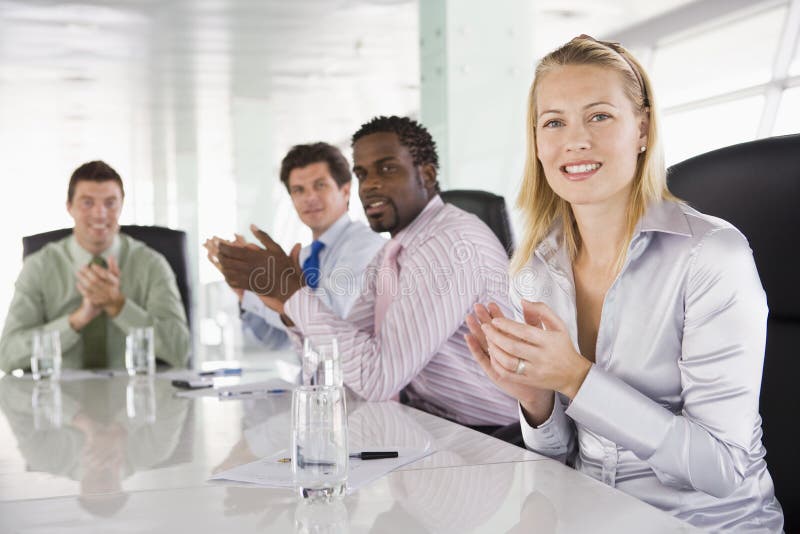 Four businesspeople in a boardroom applauding looking at camera. Boardroom table clapping stock images, royalty-free photos and pictures