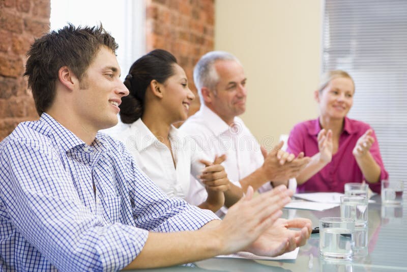 Four businesspeople in boardroom applauding and smiling. Boardroom table clapping stock images, royalty-free photos and pictures