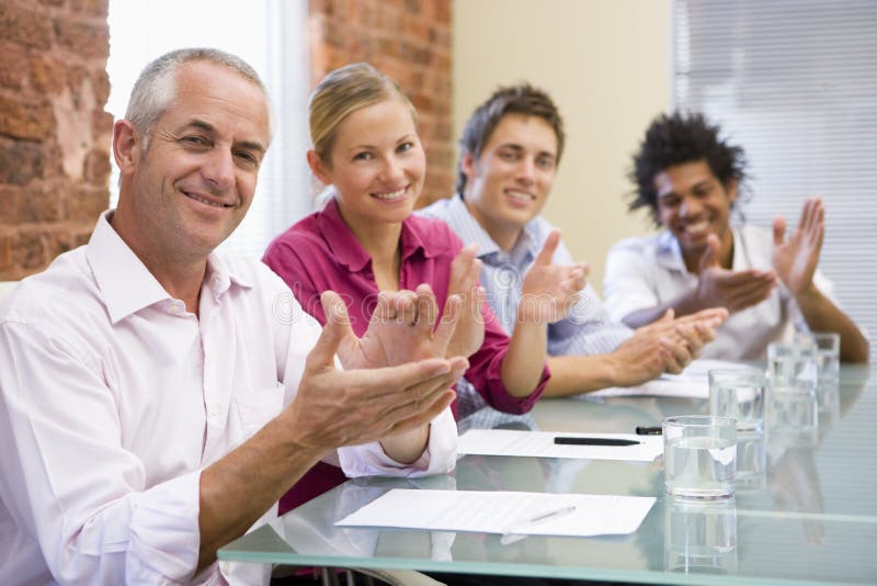 Four businesspeople in boardroom applauding to camera. Boardroom table clapping stock images, royalty-free photos and pictures